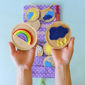 hands-holding-rainbow-and-storm-symbols-above-educational-weather-chart